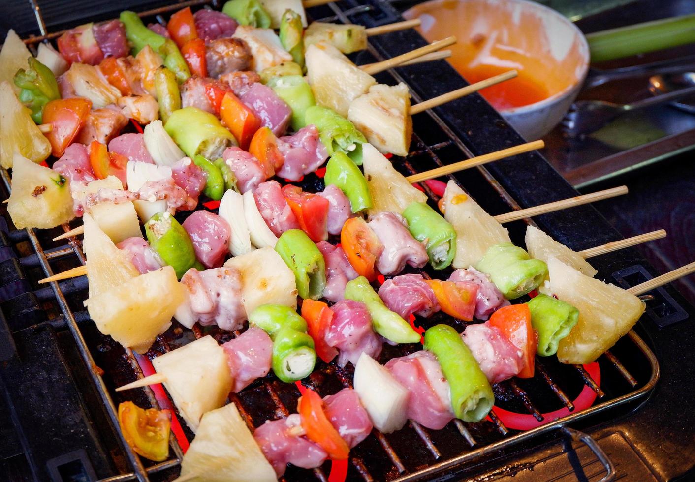 carne de cerdo asada a la barbacoa y frutas vegetales con salsa palitos de brocheta para barbacoa a la parrilla en la parrilla de la estufa foto