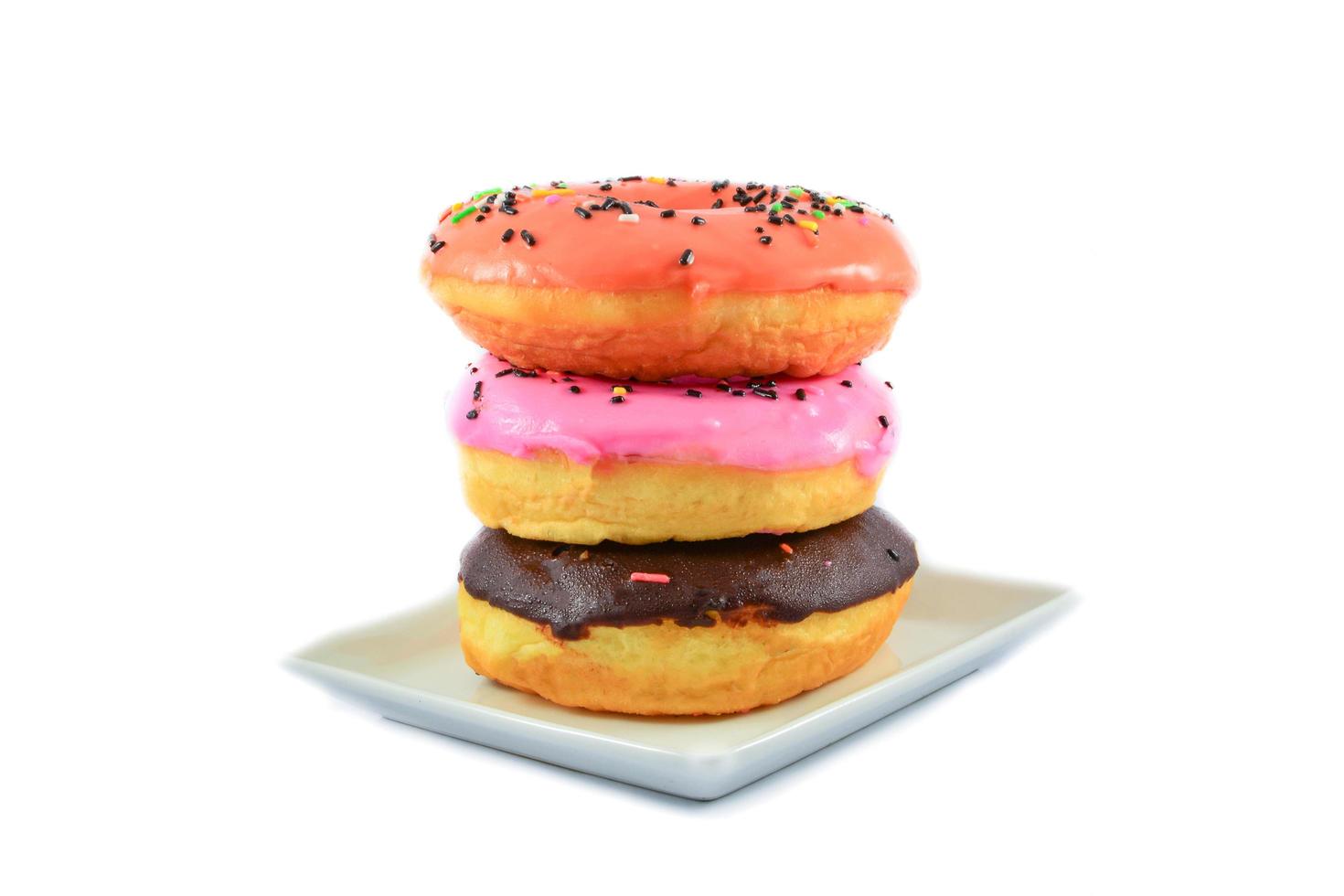 Deliciosos donuts coloridos en placa blanca aislado sobre fondo blanco. foto