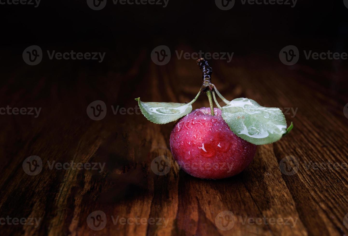 Red ripe apple with leaves on a wooden table. photo