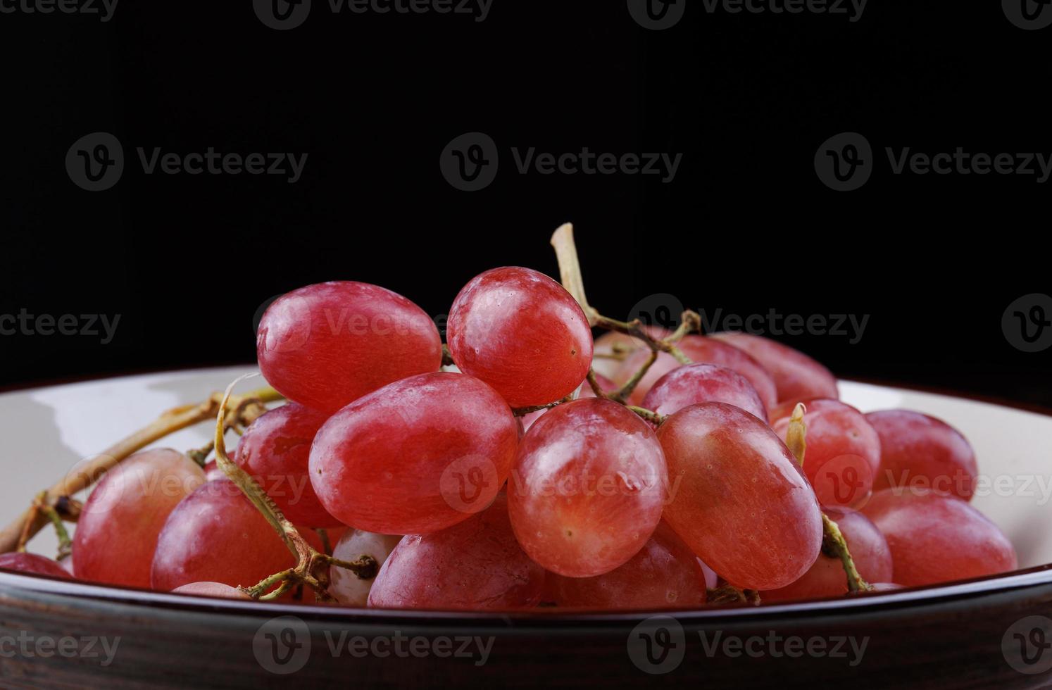 Bunch of ripe red grapes in a plate side view. Red grape Taifi photo
