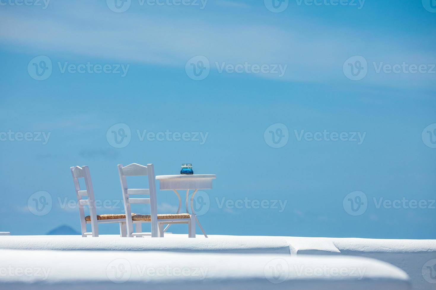 Romantic table set-up in Santorini Greece. White architecture and table for two. Love concept in romantic travel destination, summer holiday or vacation concept. photo
