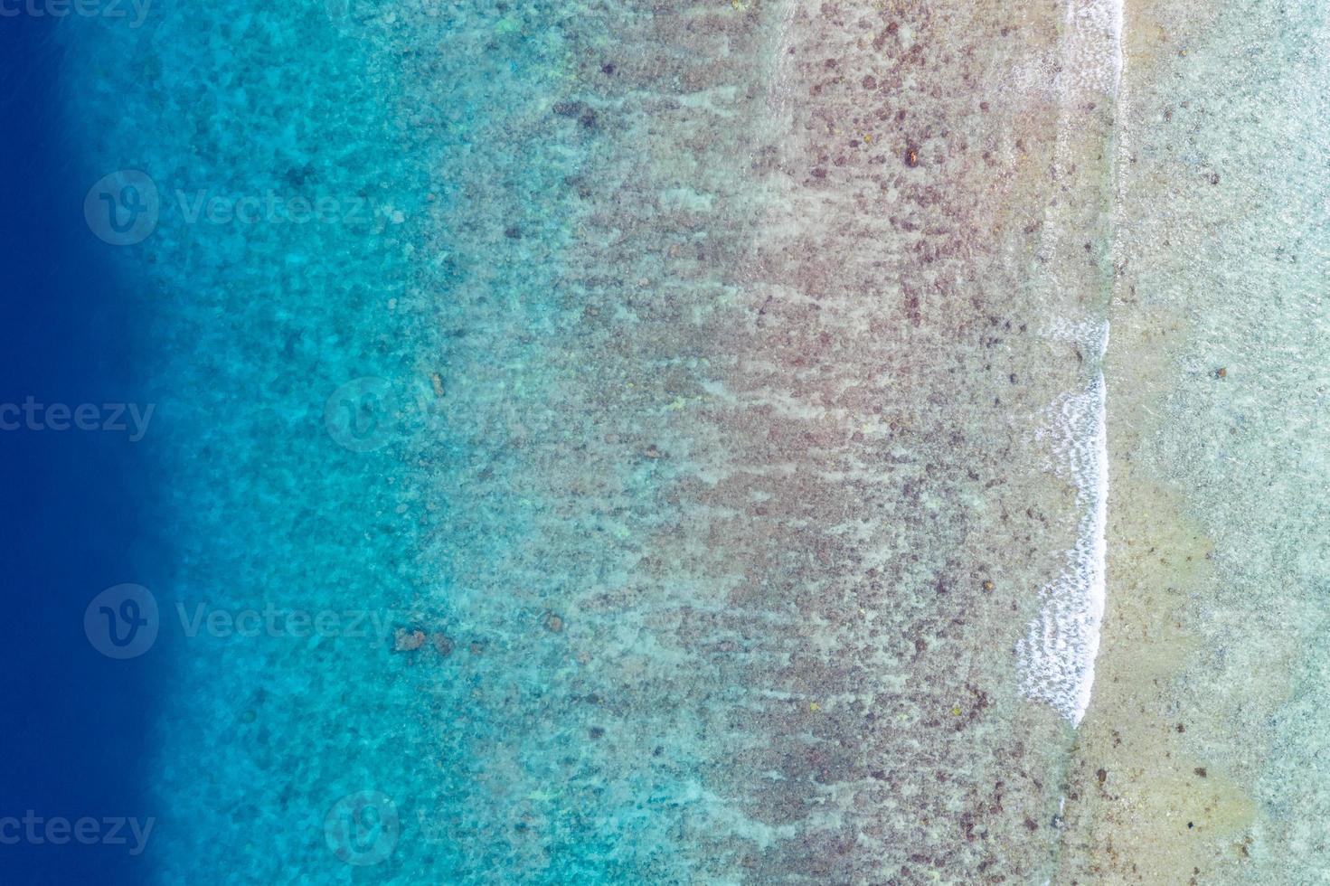 vista aérea al mar, vista superior del increíble fondo del océano natural. colores de agua azul brillante, playa de la laguna con olas salpicando en el día soleado. foto de drones voladores, asombroso paisaje natural con arrecife de coral