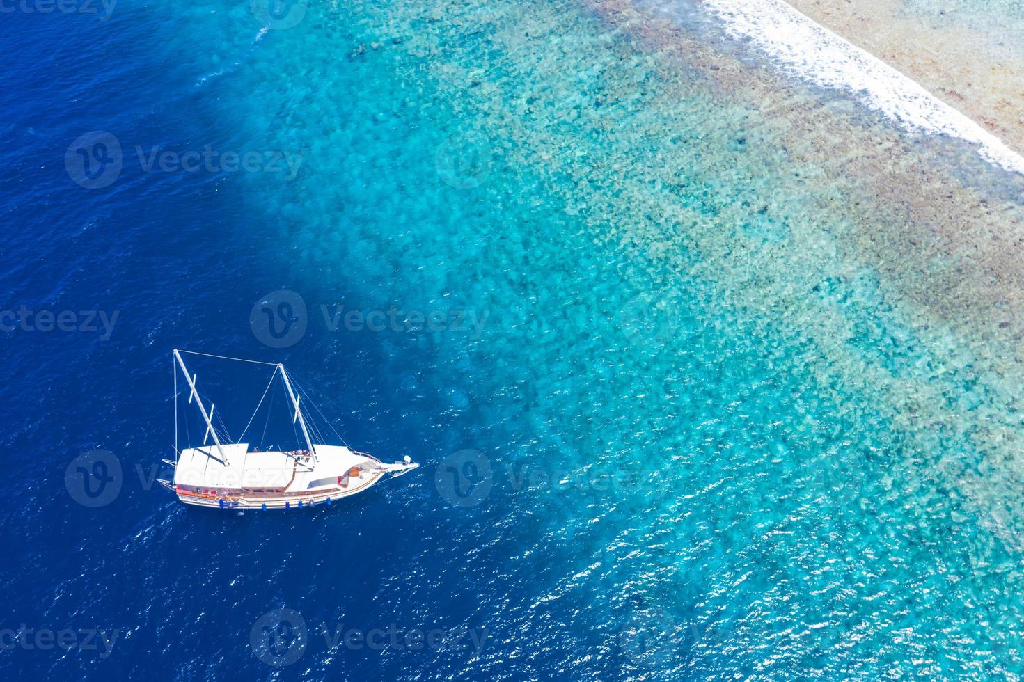 Aerial view of sailing boat anchoring on coral reef. Drone view, water sport theme. Luxury cruise and marine travel background. Beautiful nature scenery, sea ocean water concept. Maldives aerial photo