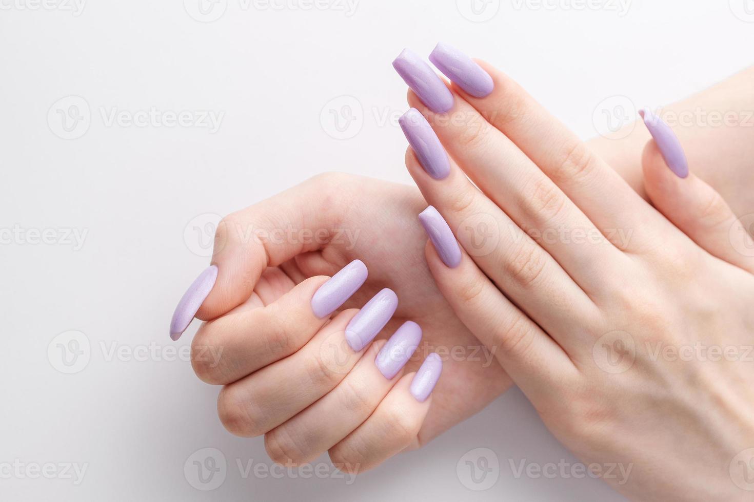 manos de una chica con una manicura violeta suave sobre un fondo blanco. foto