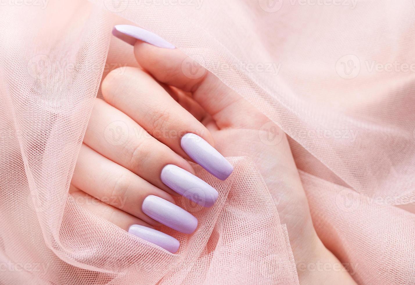 manos de niña con una manicura violeta suave. foto