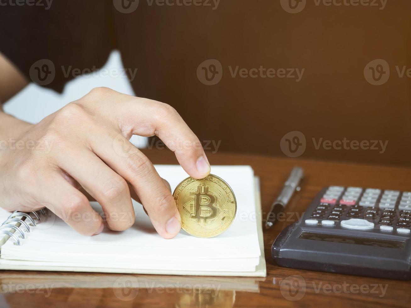 Close up hand hold bitcoin on workspace on the desk photo