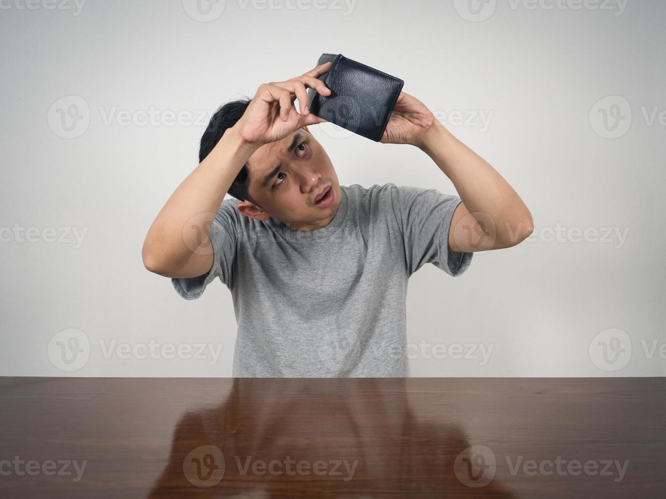 Young man sitting and hold wallet finding money feels sad photo