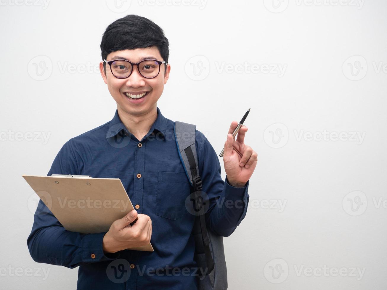 Man wearing glasses holding clipboard with backpak point pen at copy space photo