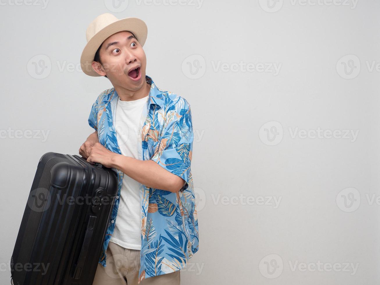 Young man wear hat beach shirt feels amazed with holiday hold luggage photo