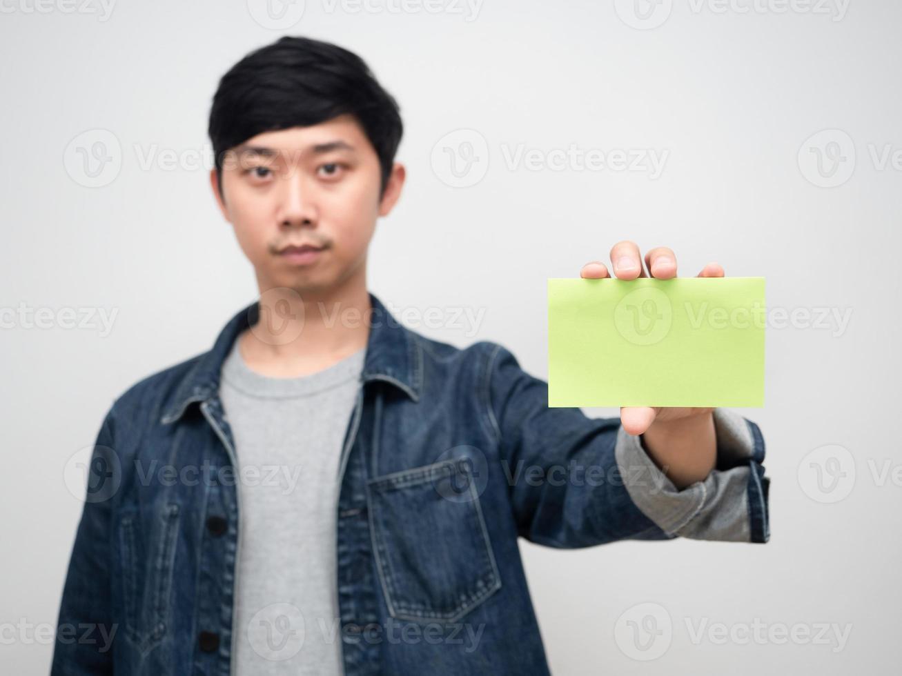 Positive young man jeans shirt holding empty post it white background photo