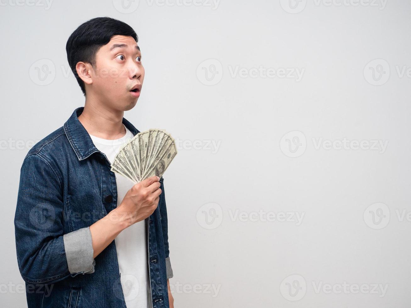 camisa de jeans de hombre emocionado mantener dinero mirando el espacio de copia foto