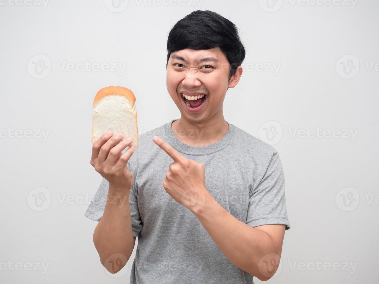 Cheerful asian man point finger at bread in hand portrait isolated photo