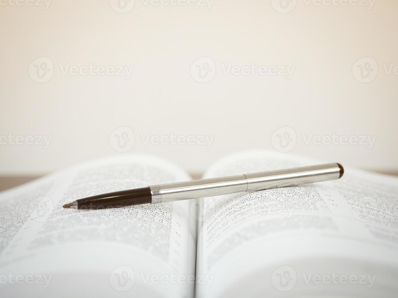 Pen on open text book white background photo