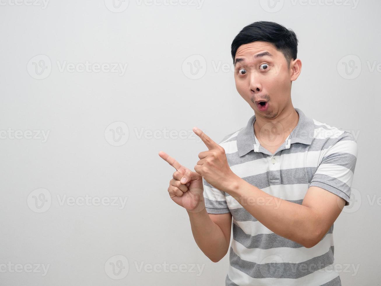 Cheerful man feels amazed point double finger at copy space photo