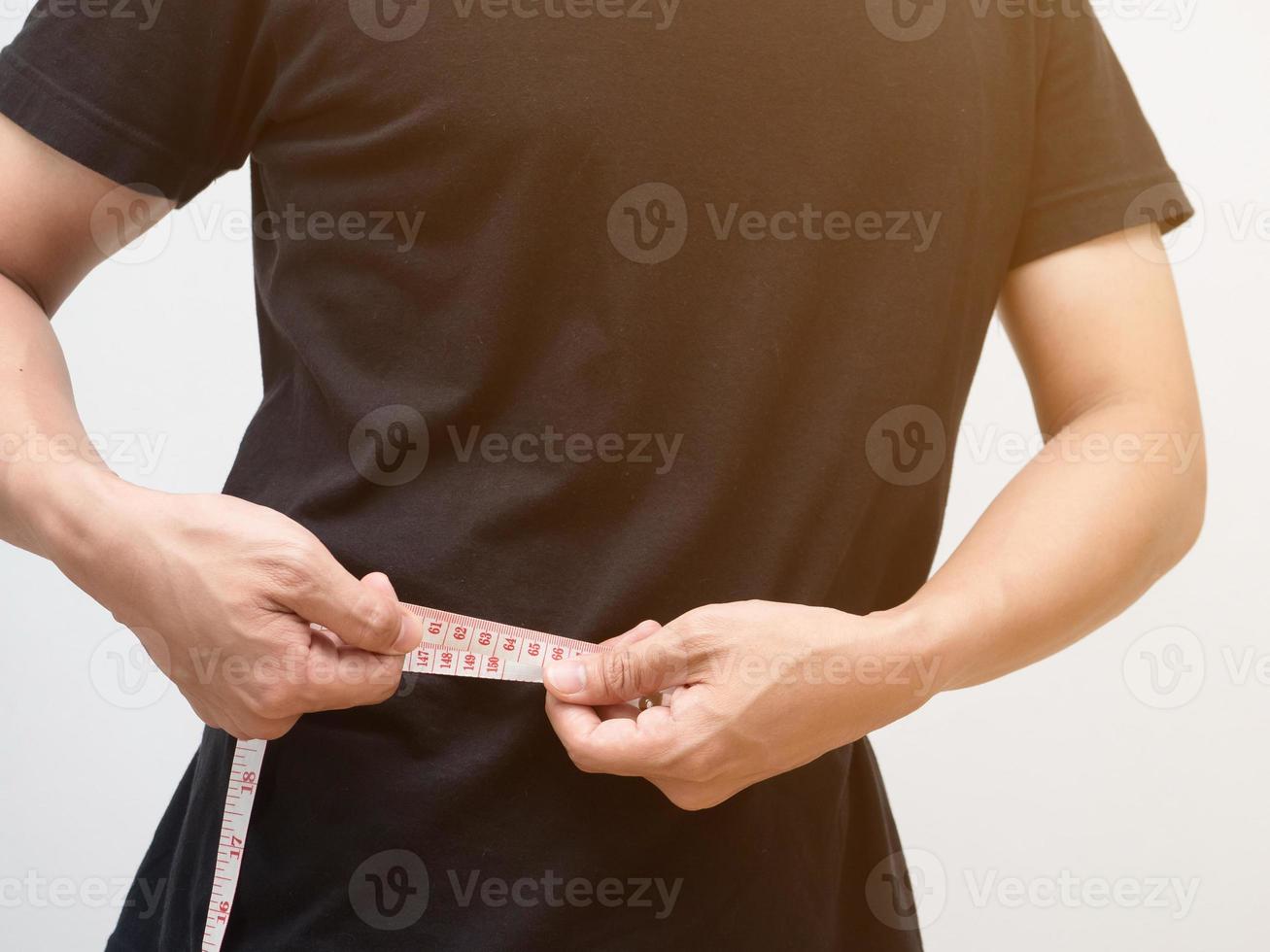 Closeup man using measure tape body for checking his waist white background photo