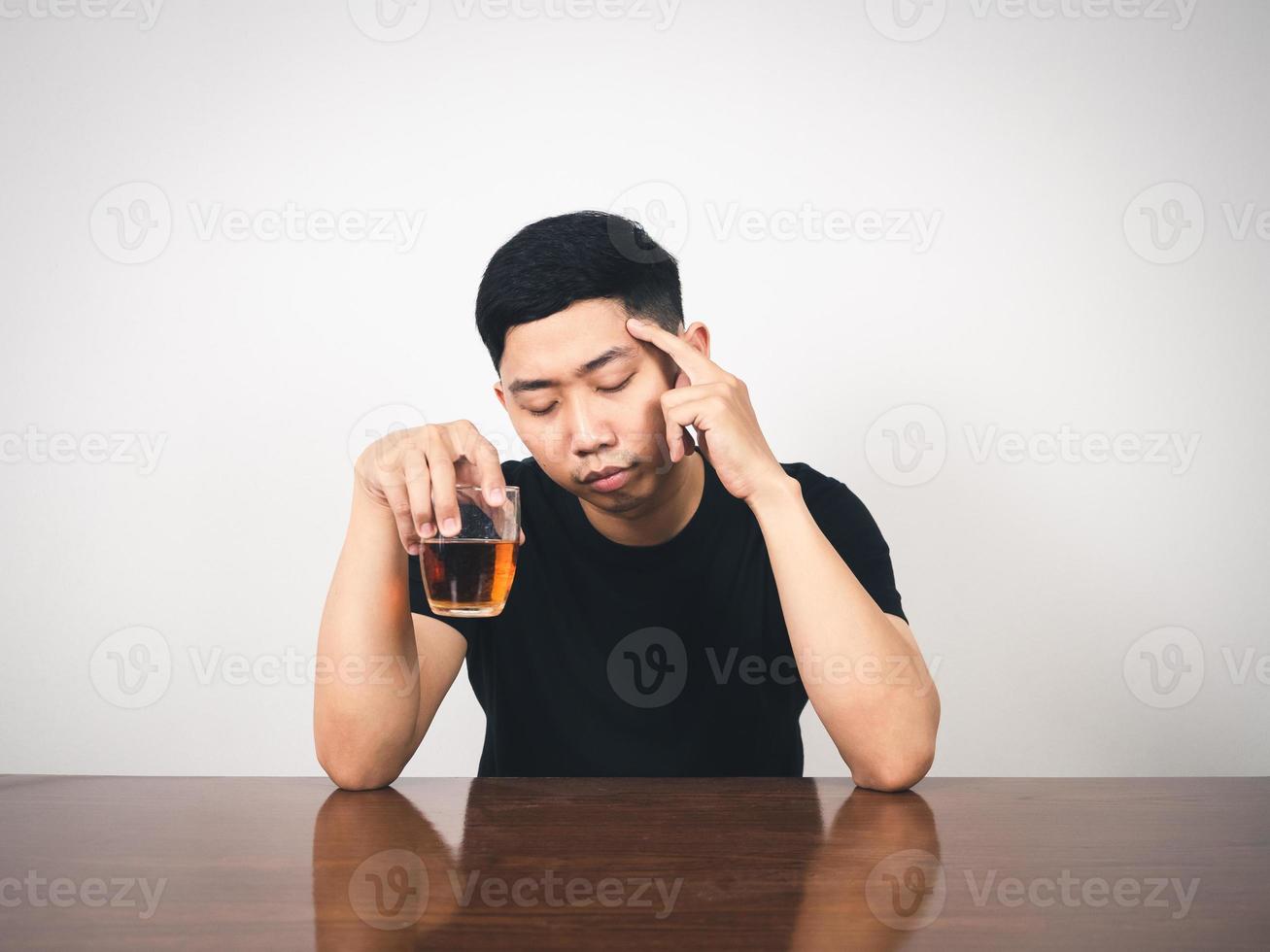 Drunk man sit and hold glass of alcohol in hand photo