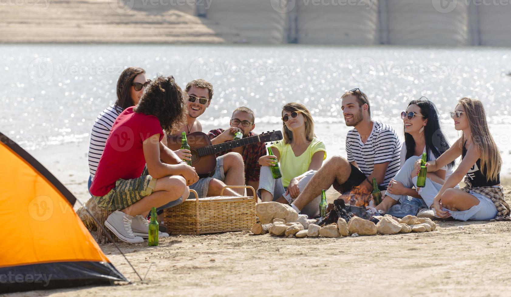 verano, vacaciones, vacaciones, música, concepto de gente feliz - grupo de amigos con guitarra divirtiéndose en la playa foto