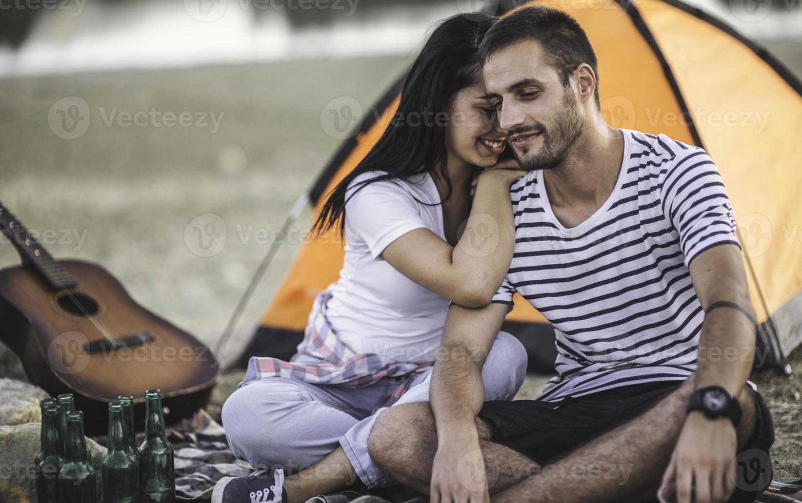 Picnic holiday concept. Beautiful couple having fun making BBQ on bonfire and relaxing by a lake. photo