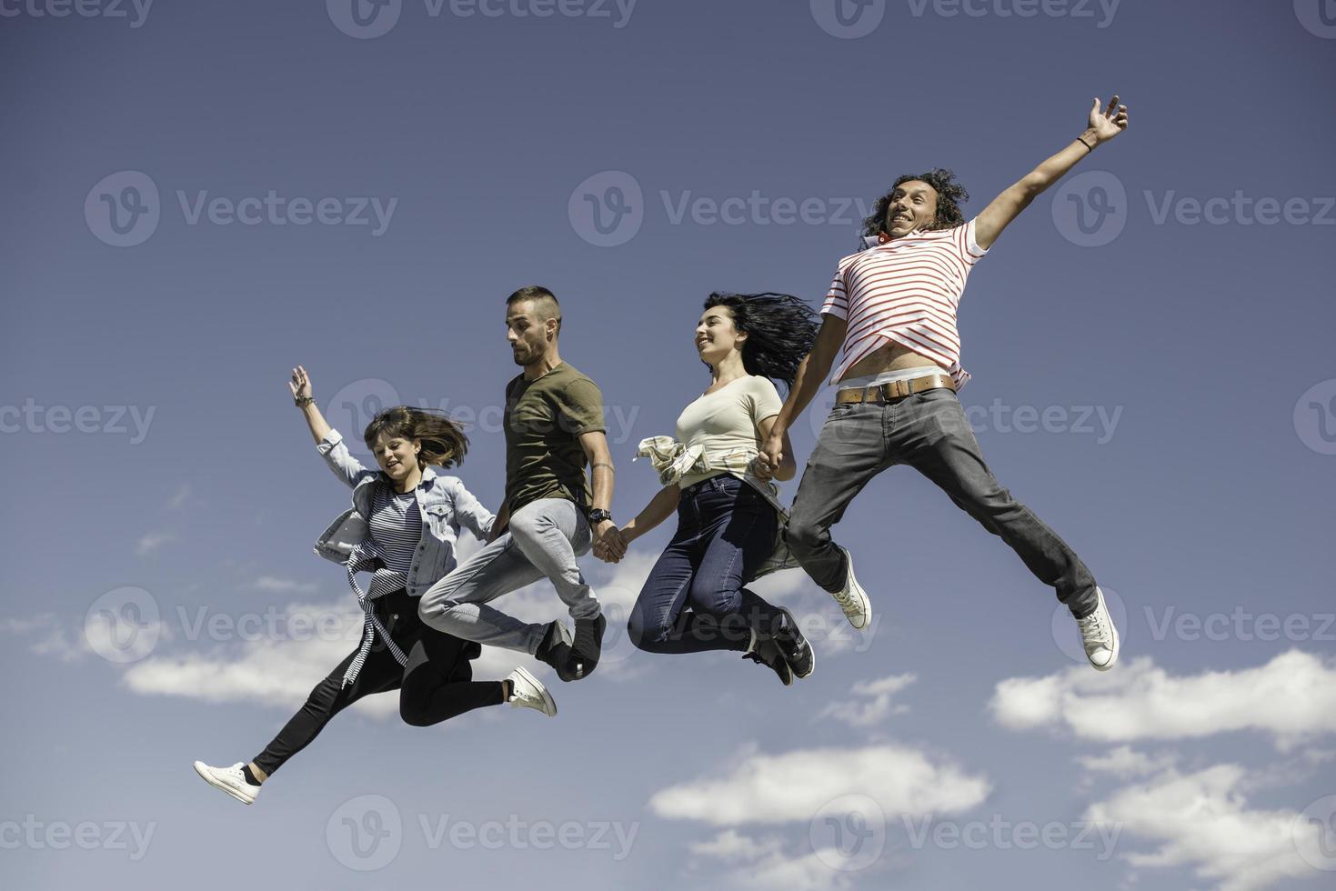 Portrait of young friends jumping from jetty into lake. Friends in mid air on a sunny day at the lake. photo