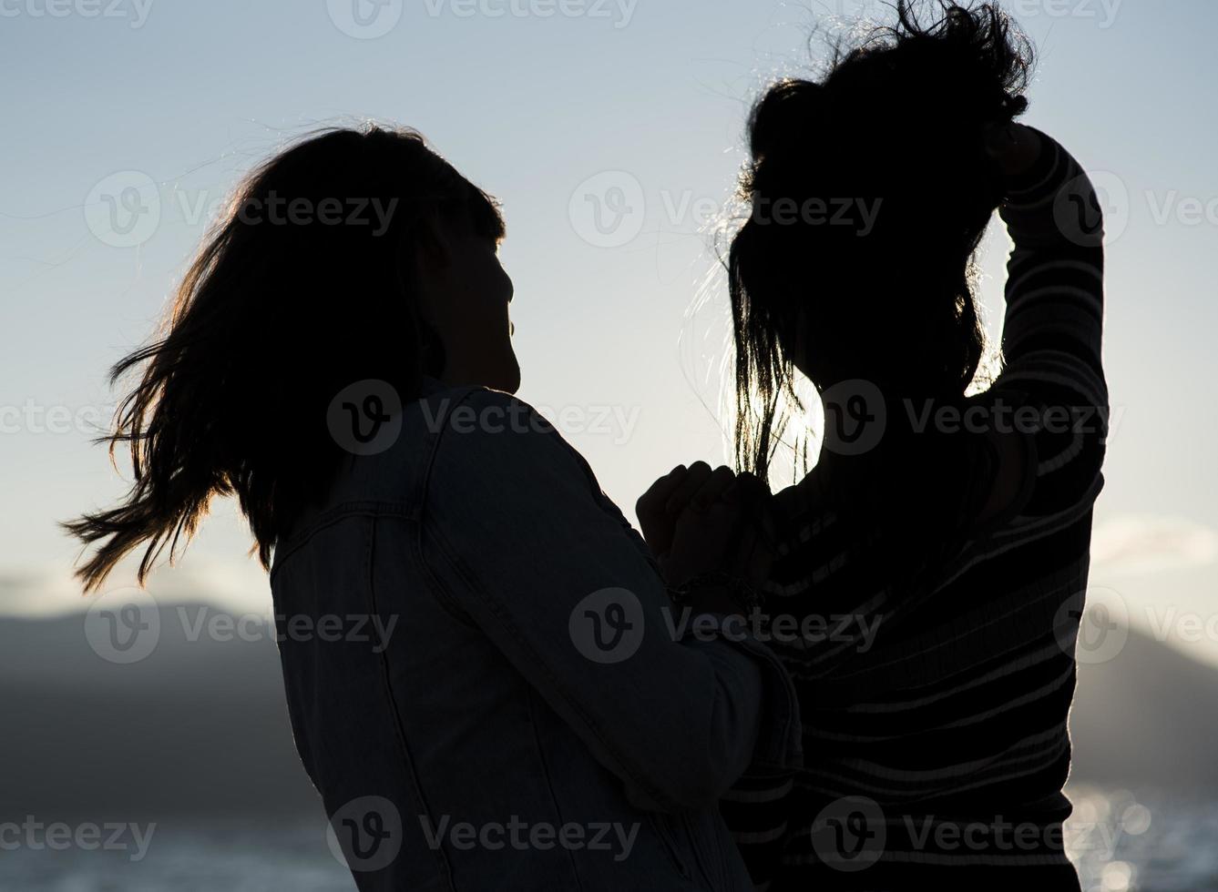 siluetas de novias al atardecer abrazándose. foto