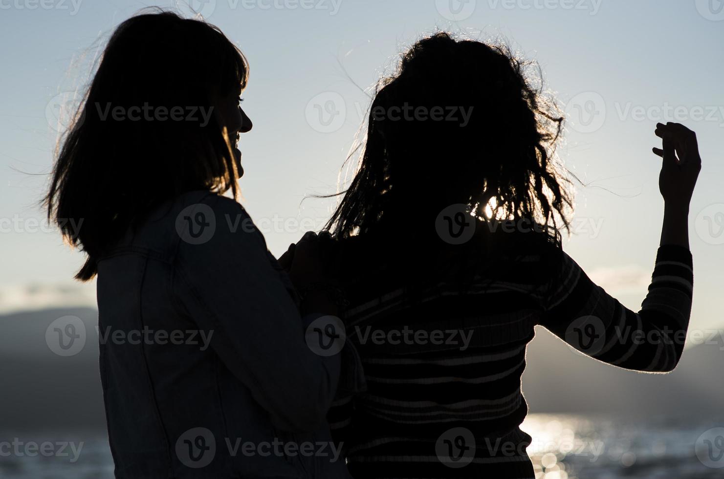 siluetas de novias al atardecer abrazándose. foto