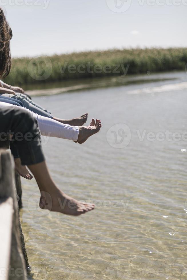 couple of friends relaxing on the pear by a lake. summer vacation concept photo
