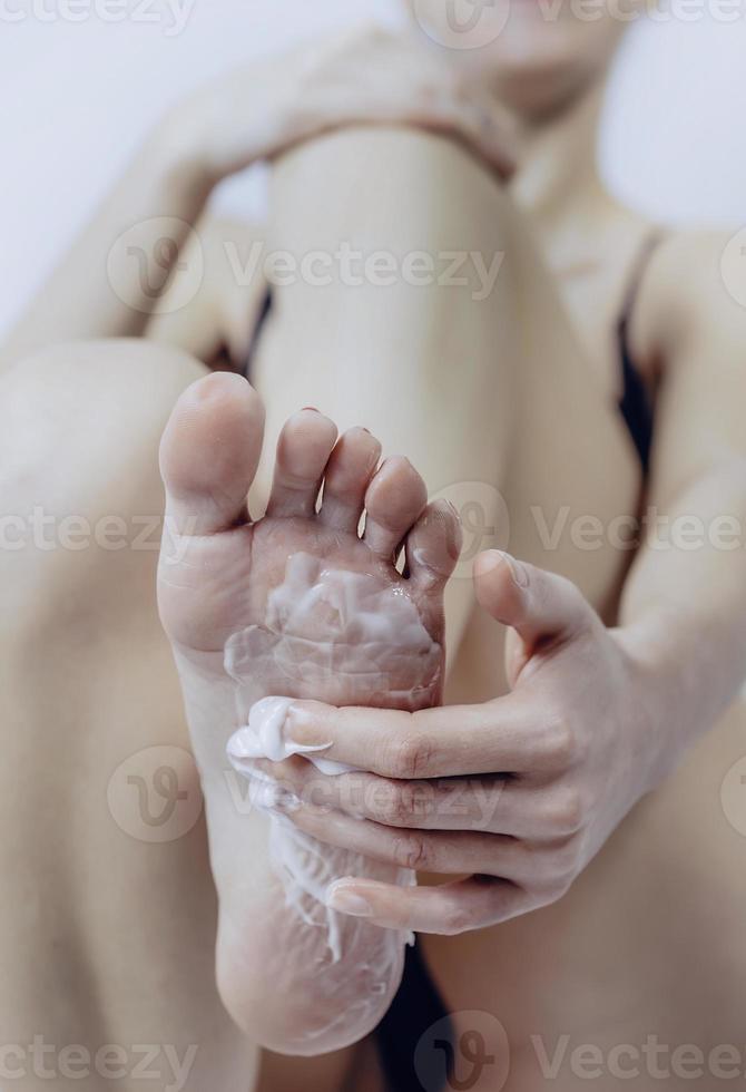 foot care. woman putting cream on the bottom of her foot. photo
