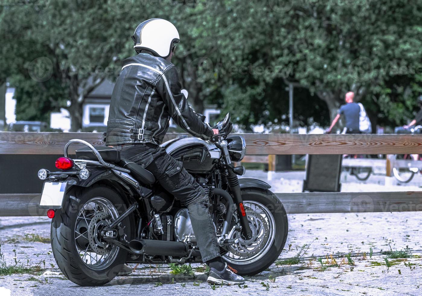 Back view photo of handsome young man biker on bike outdoors