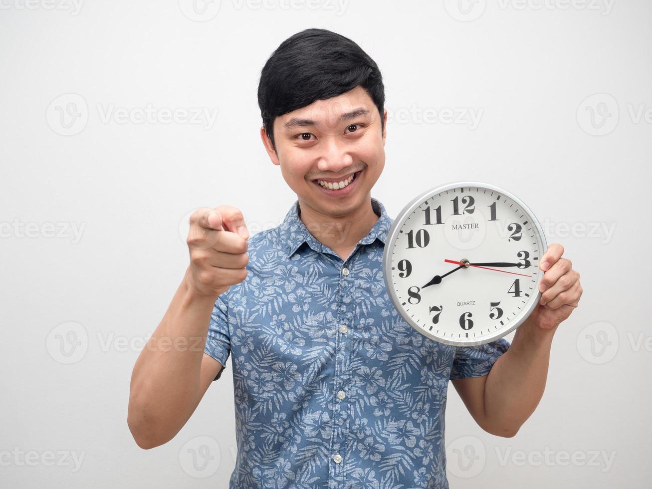 hombre alegre que sostiene el reloj sonriendo señalar con el dedo aislado foto