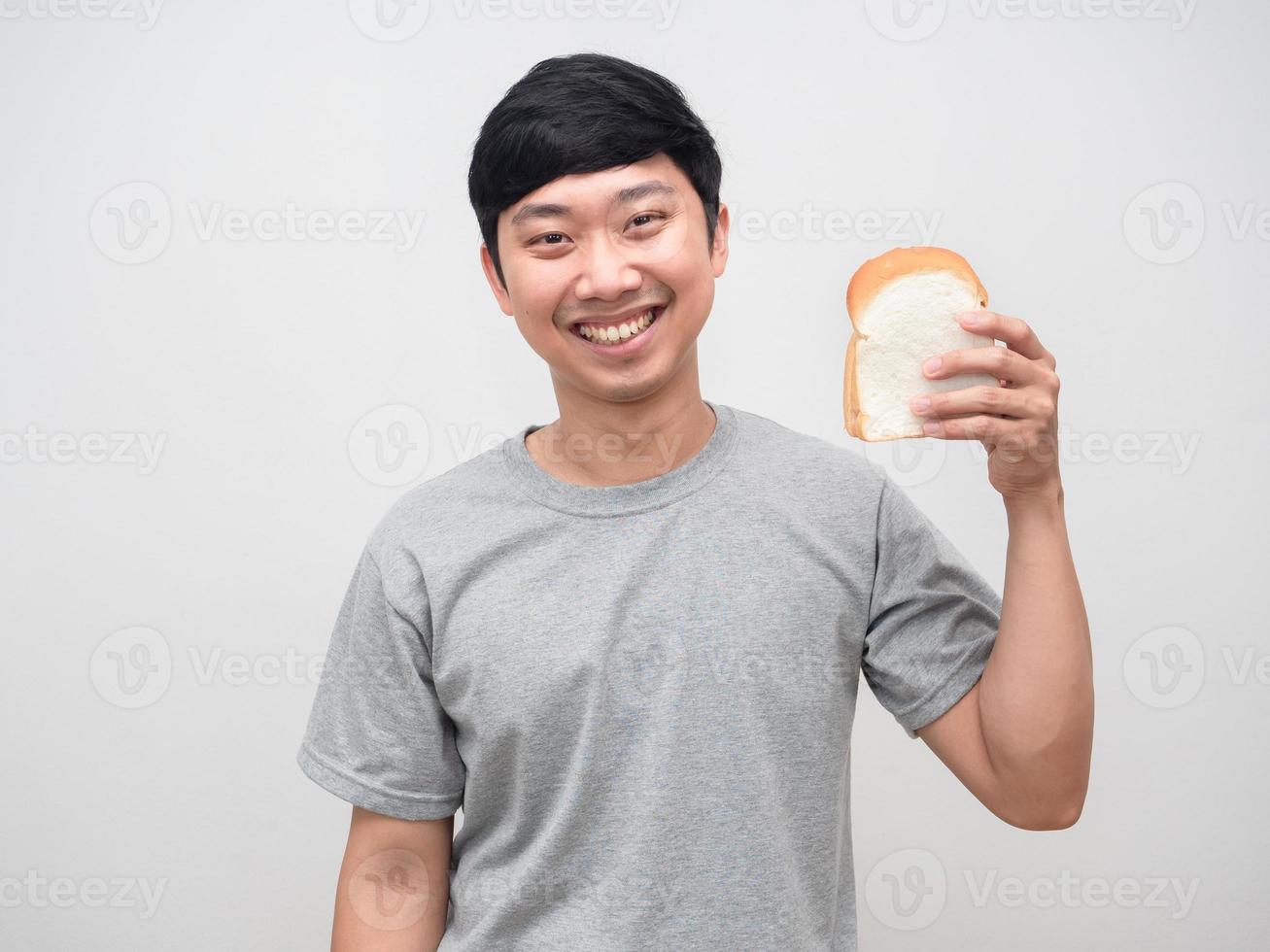 Young positive man gentle smile holding bread portrait photo