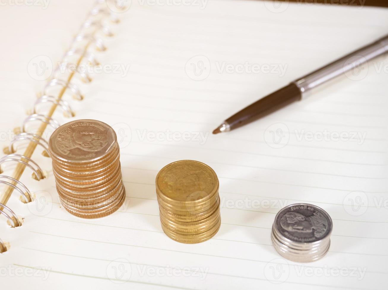 crecimiento de monedas con pluma en libro abierto foto