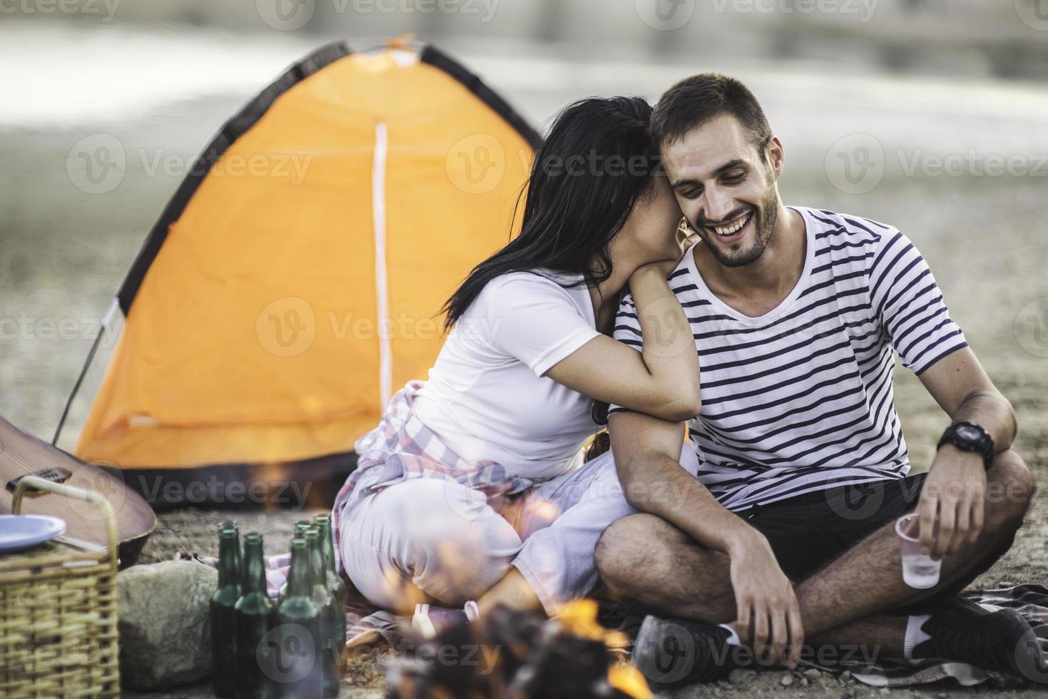 Picnic holiday concept. Beautiful couple having fun making BBQ on bonfire and relaxing by a lake. photo