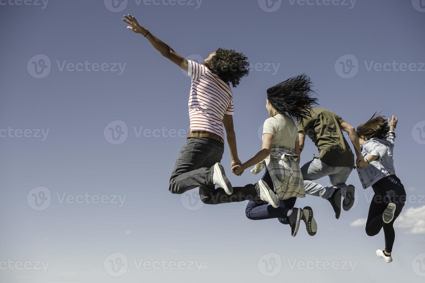 Portrait of young friends jumping from jetty into lake. Friends in mid air on a sunny day at the lake. photo