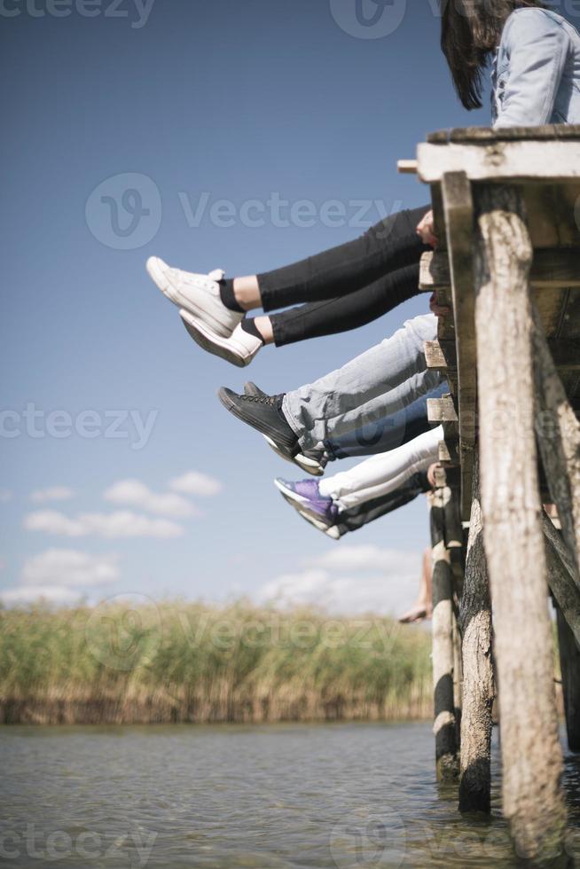 couple of friends relaxing on the pear by a lake. summer vacation concept photo