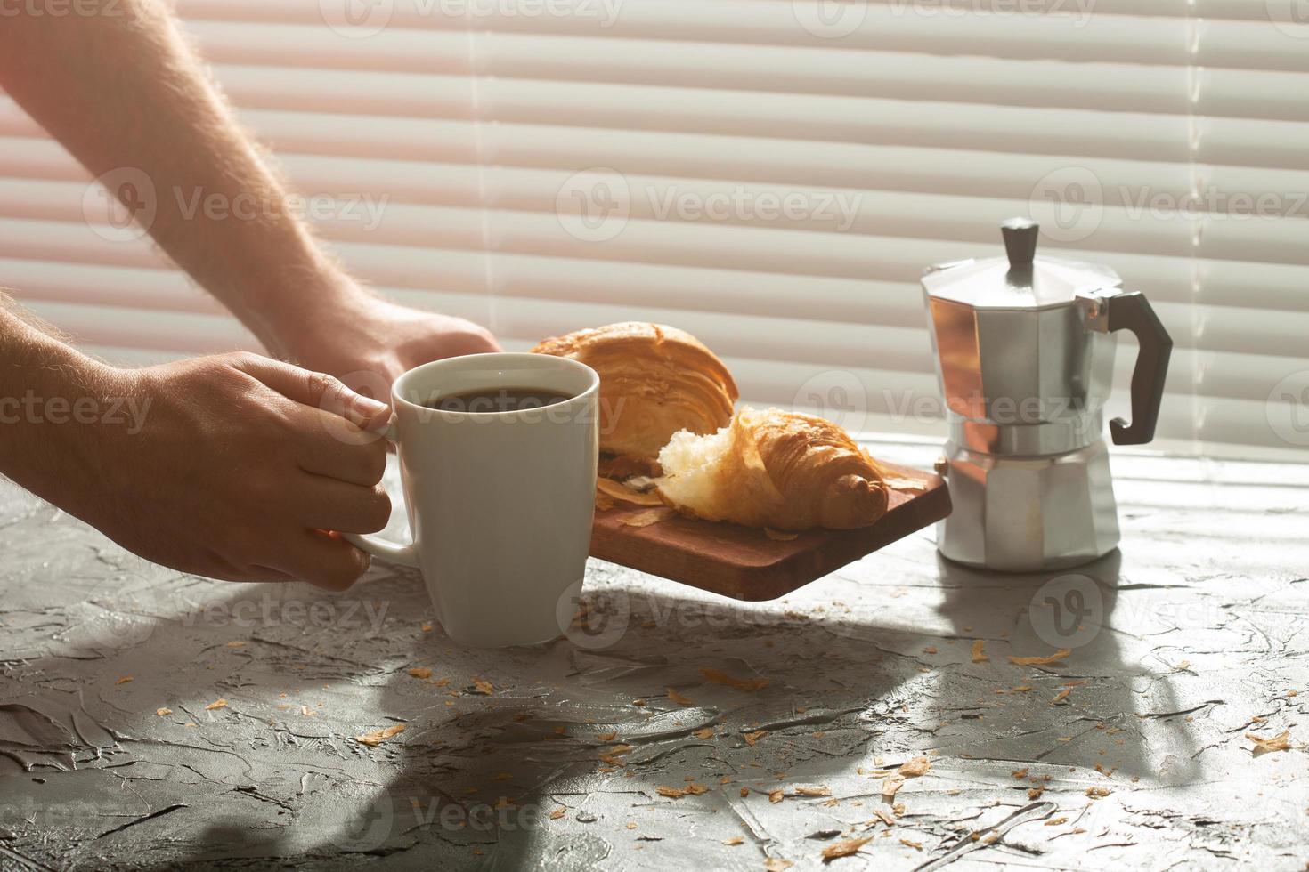 Breakfast with croissant on cutting board and black coffee. Morning meal and breakfast concept. photo