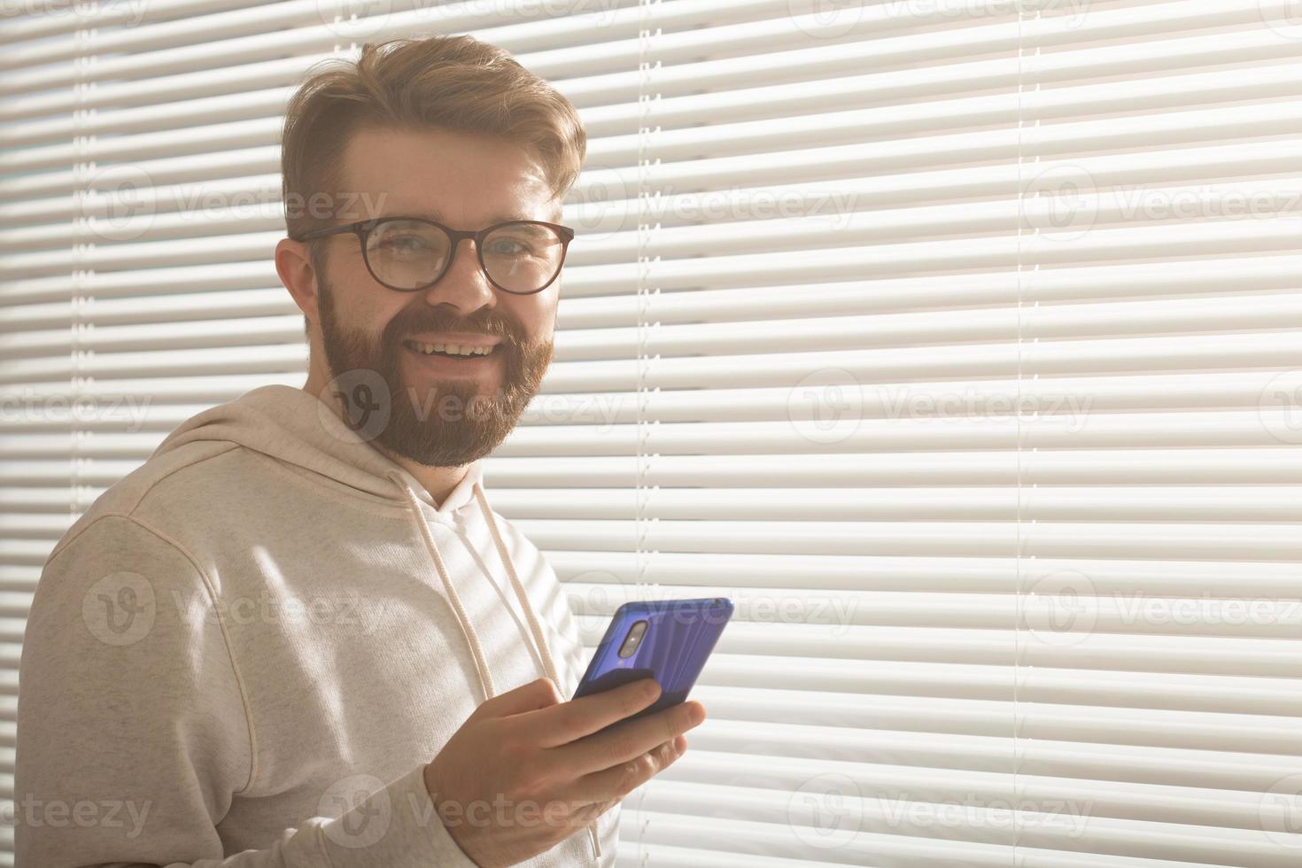 Happy man using mobile phone at home or at office, copy space photo