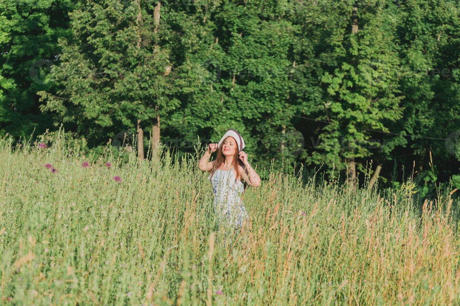 Woman walking in a field in summer sunny day. photo