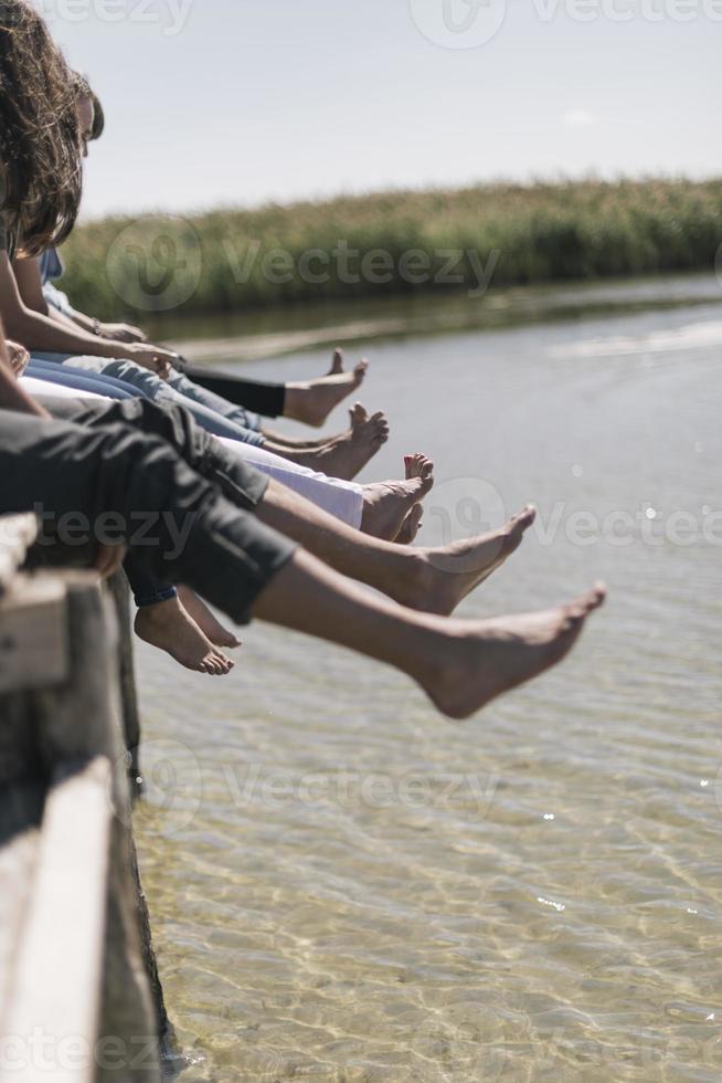 couple of friends relaxing on the pear by a lake. summer vacation concept photo