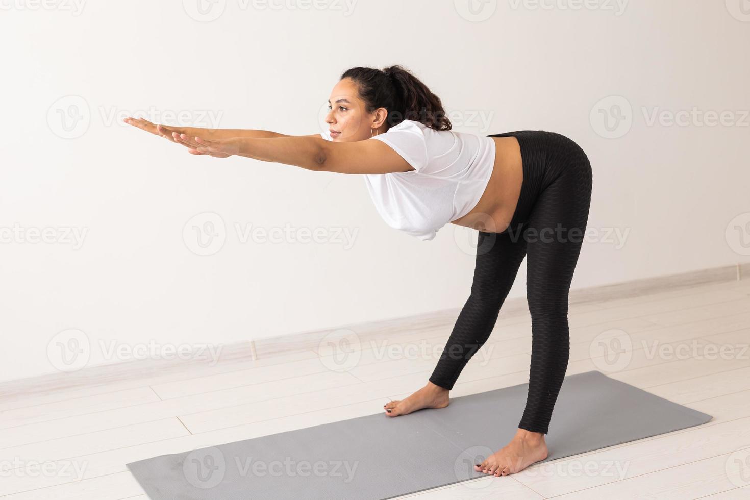 Young flexible pregnant woman doing gymnastics on rug on the floor on white background. The concept of preparing the body for easy childbirth photo