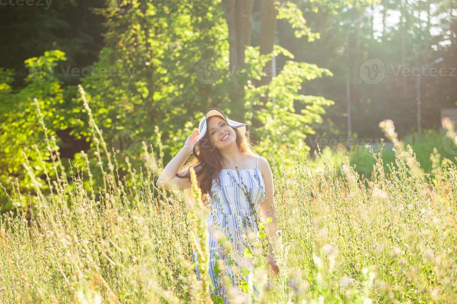 Young woman walking among wildflowers on sunny summer day. Concept of the joy of communicating with summer nature photo