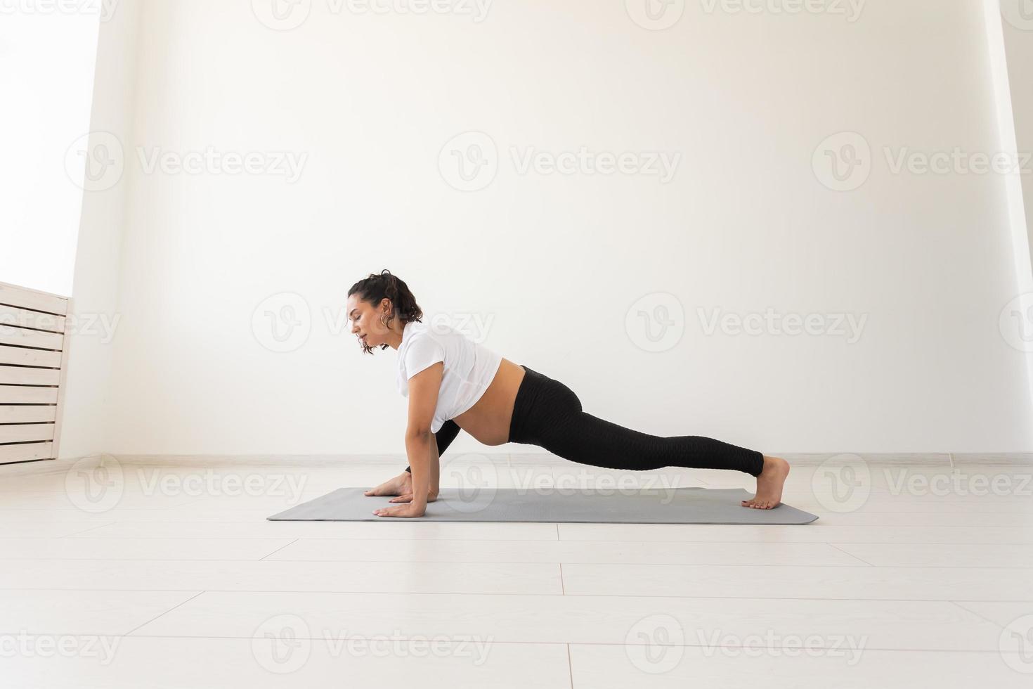 Purposeful pregnant woman exercises during yoga class and relaxes while sitting on a mat on the floor. Concept of physical and mental preparation of the body for childbirth. Place for text photo