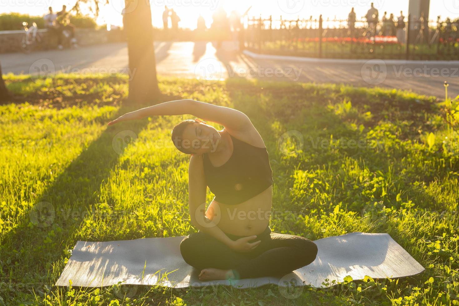 Pregnant woman doing yoga in nature outdoors. Healthy lifestyle, expecting baby and childbearing concept. photo