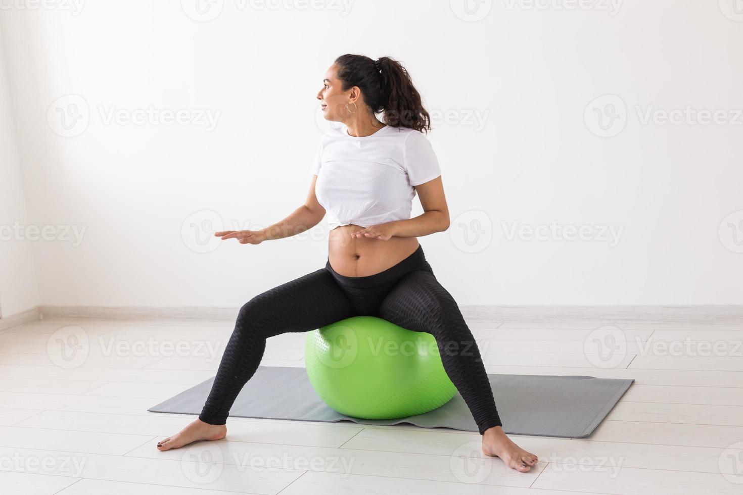 Cheerful pregnant woman dances while sitting on fitness ball. Well-being pregnancy, healthy lifestyle and positive concept. photo