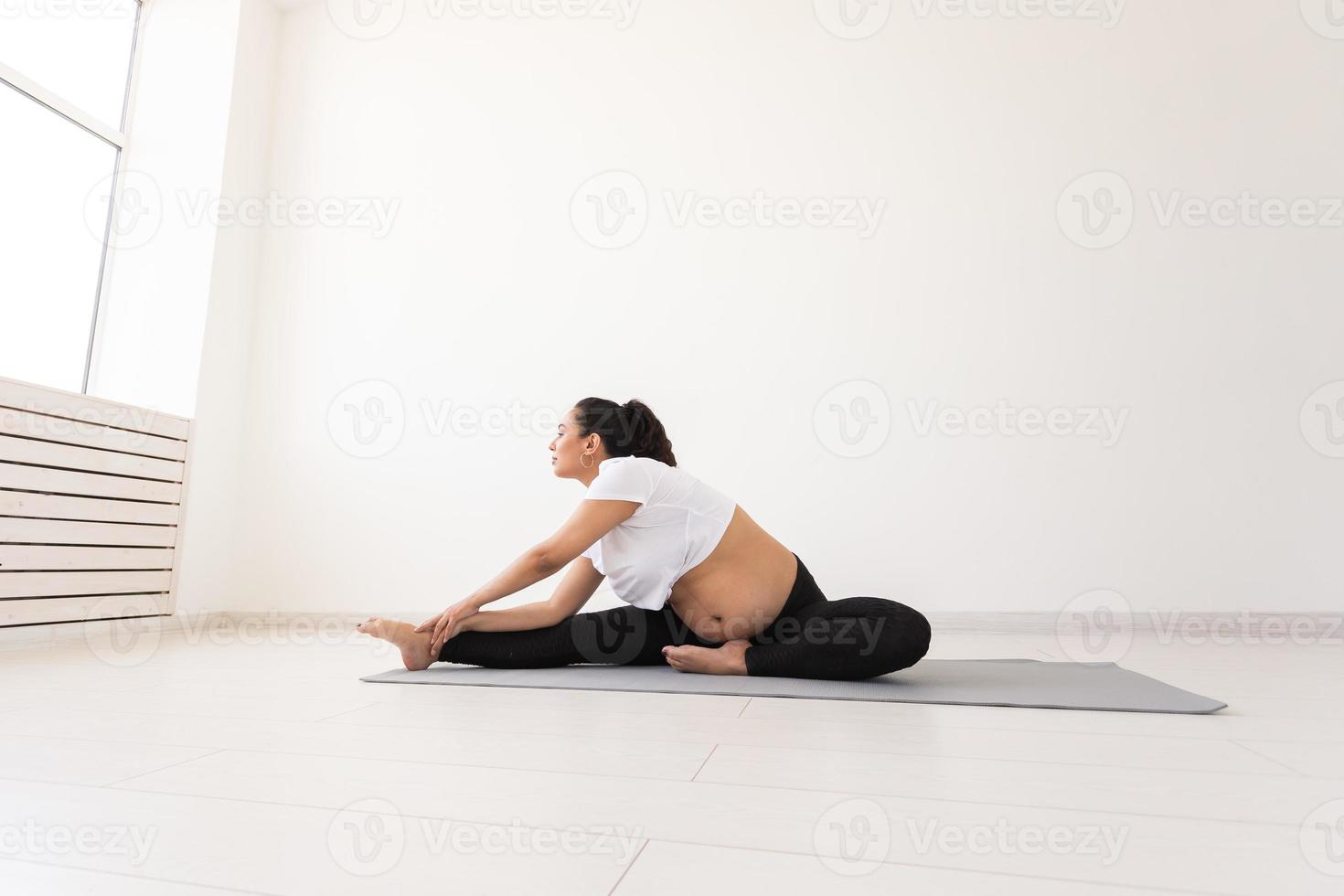 Purposeful pregnant woman exercises during yoga class and relaxes while sitting on a mat on the floor. Concept of physical and mental preparation of the body for childbirth. Place for text photo