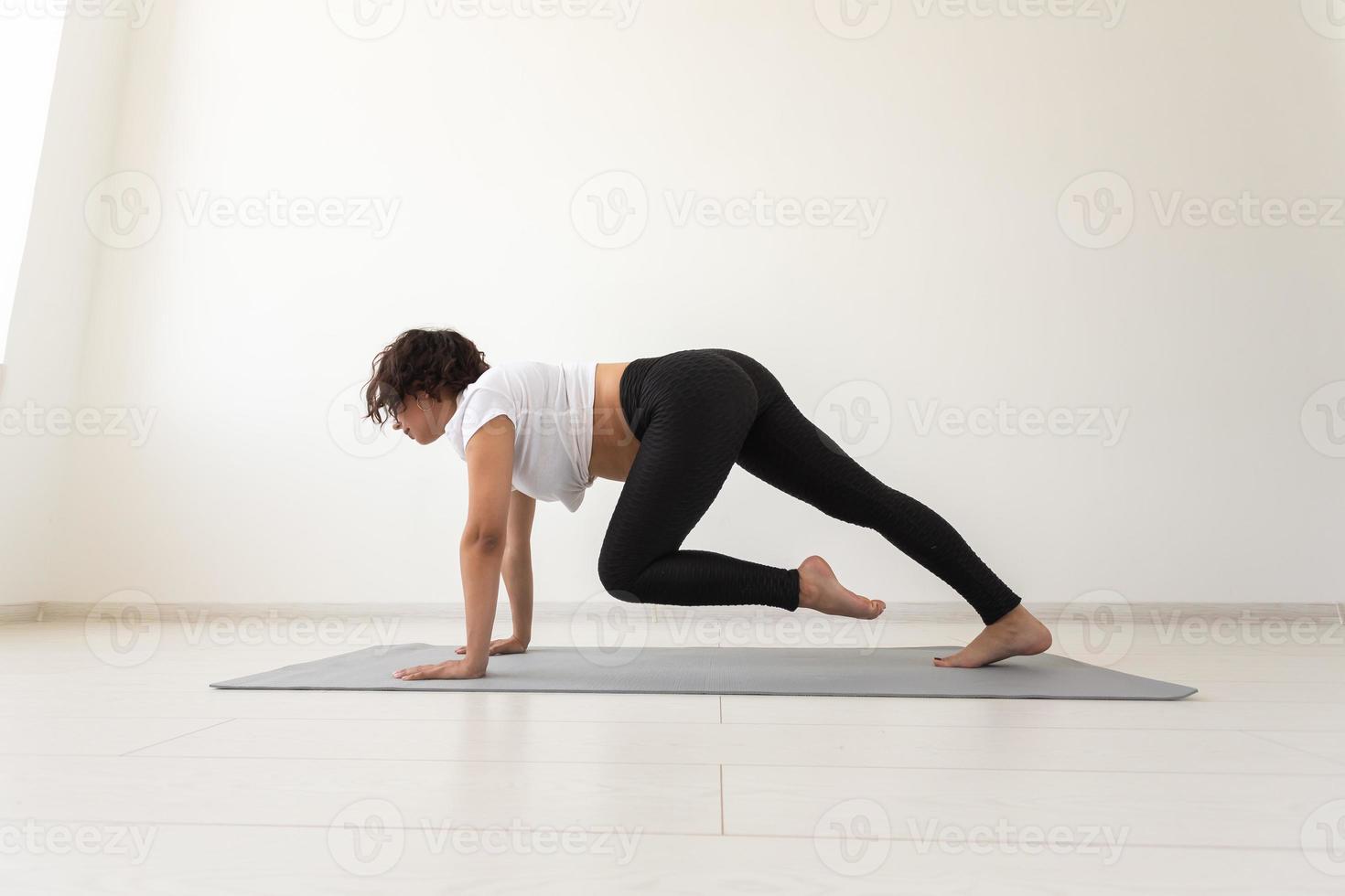 Young flexible pregnant woman doing gymnastics on rug on the floor on white background. The concept of preparing the body for easy childbirth photo