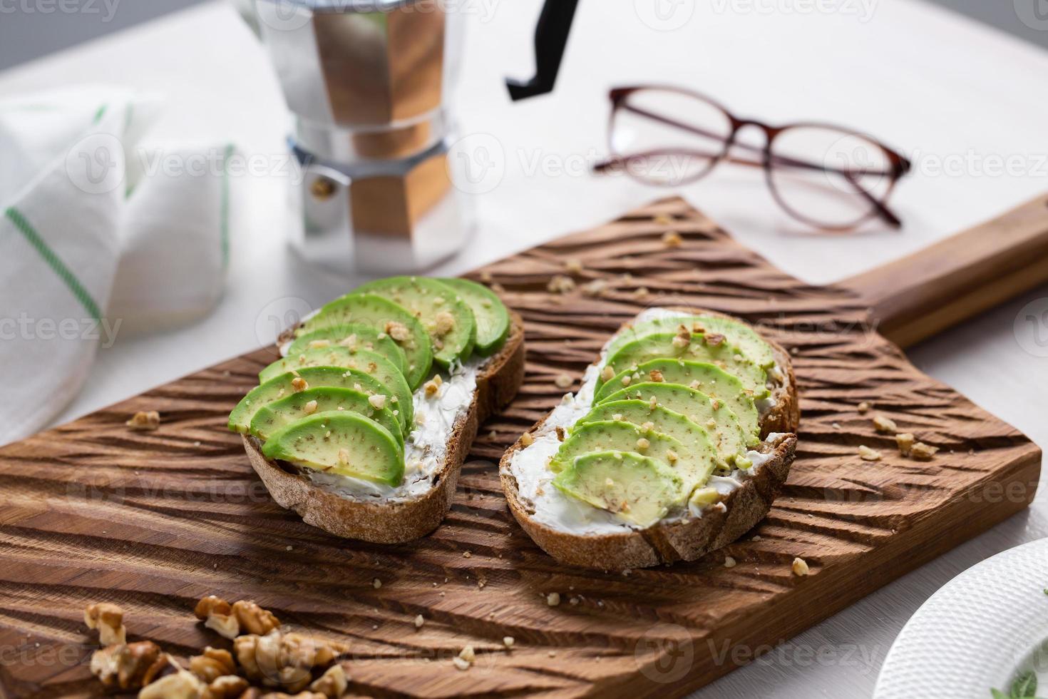 Sliced avocado on toast bread with nuts. Breakfast and healthy food concept. photo