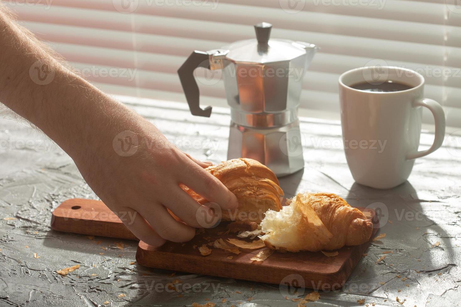 Breakfast with croissant on cutting board and black coffee. Morning meal and breakfast concept. photo