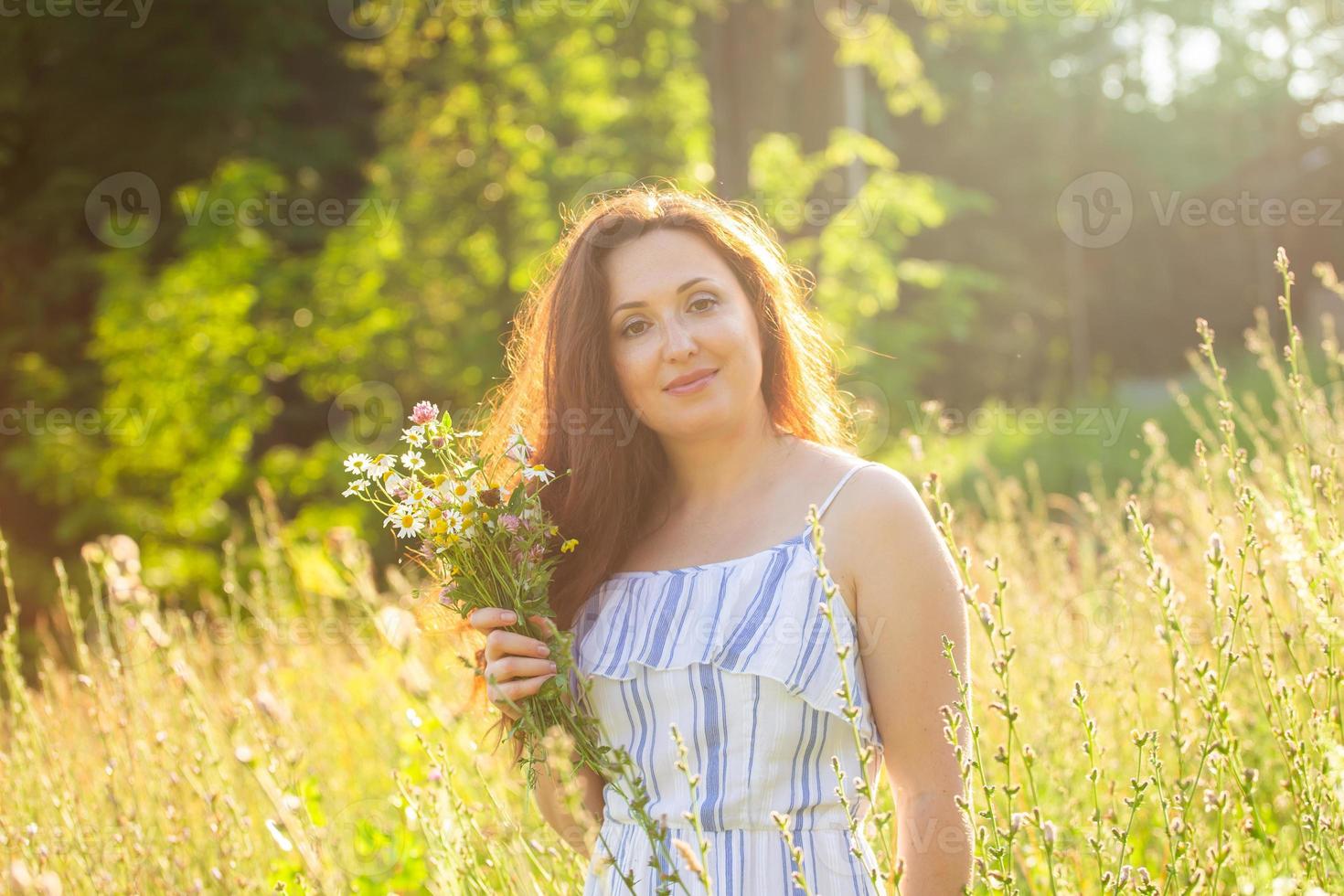 Young woman walking among wildflowers on sunny summer day. Concept of the joy of communicating with summer nature photo