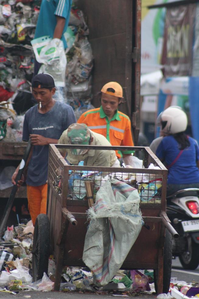 magelang,indonesia,2023-basura personas trabajando juntas vaciando el basurero para deshacerse de la basura con camiones cargando basura y basurero. foto