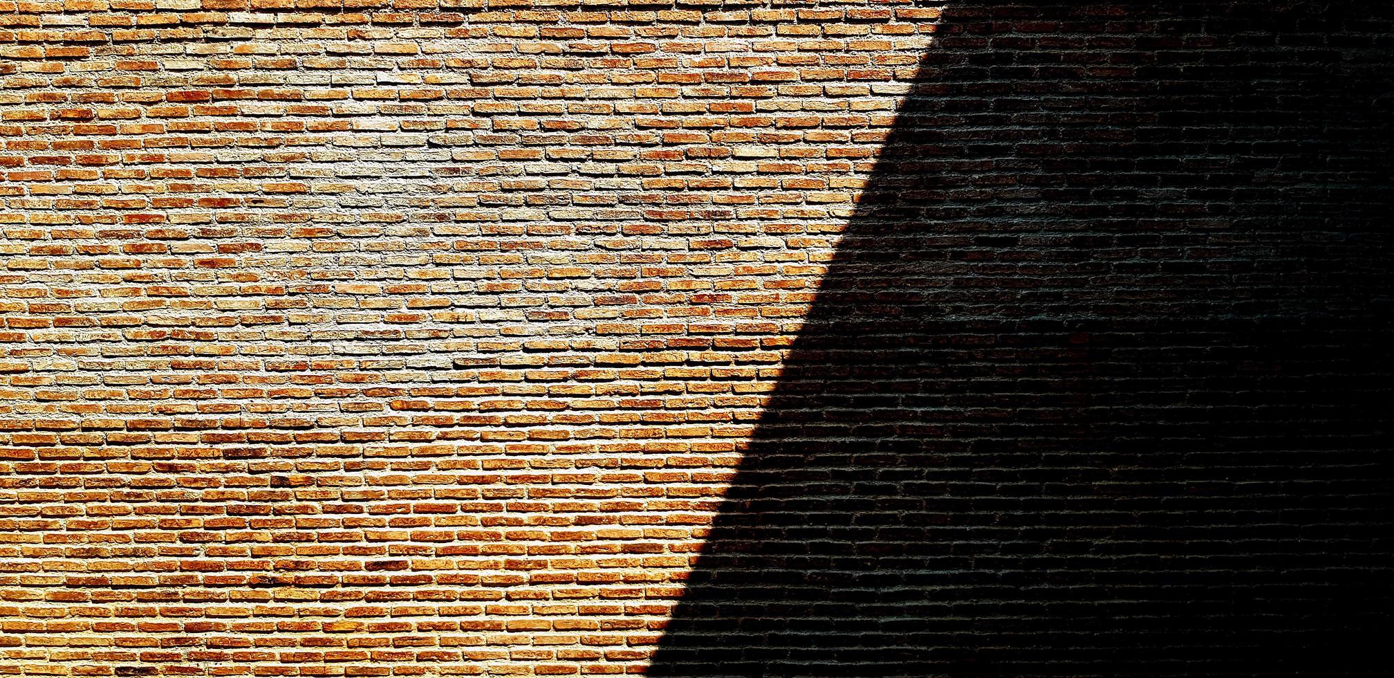 Brown or red brick wall with shadow for background. Art and Pattern wallpaper. Rough and Grunge exterior or interior design with copy space photo